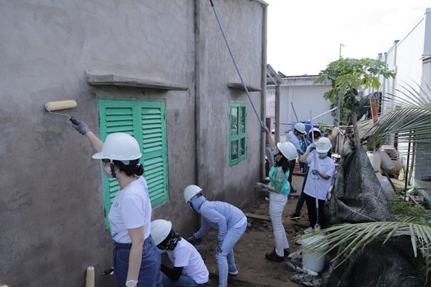 Các tình nguyện viên JTI và đối tác cùng nhau quét vôi cho bức tường tại ngôi nhà ở Tiền Giang.